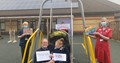 Angela Anderson, Clinical Director and Julie Sizer, Team Leader, standing either side of swing set with two pupils in the middle holding thank you signs